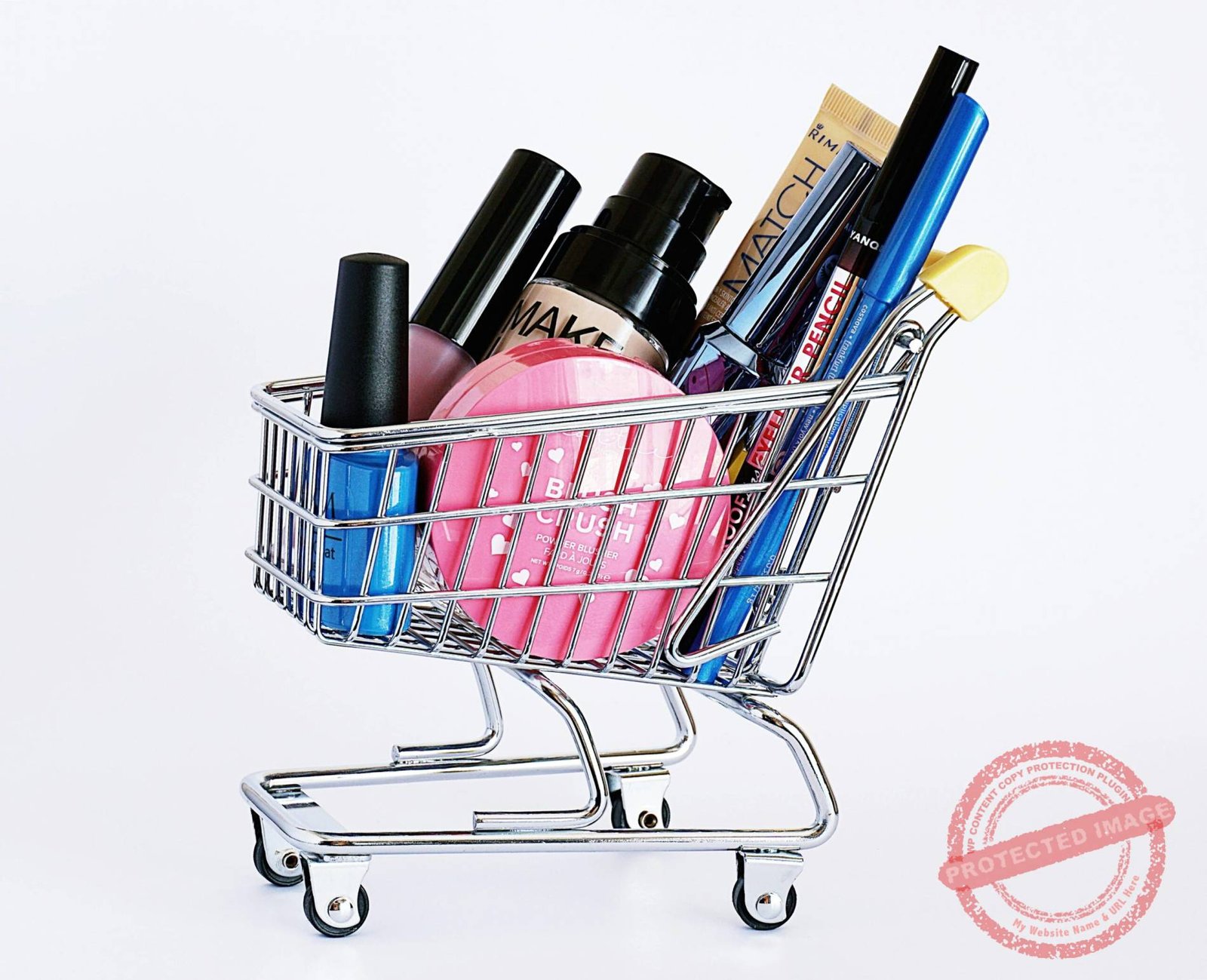 Miniature shopping cart filled with a variety of cosmetics on a white background.