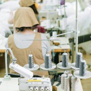 Sewing machines and workers in a textile factory, highlighting industrial manufacturing processes.